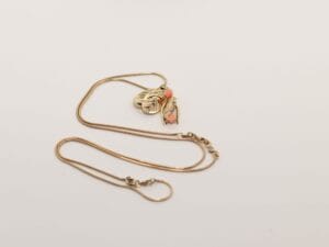 Ontwerp van gouden hanger Bird on a Wishbone met zwaluw en roze accenten